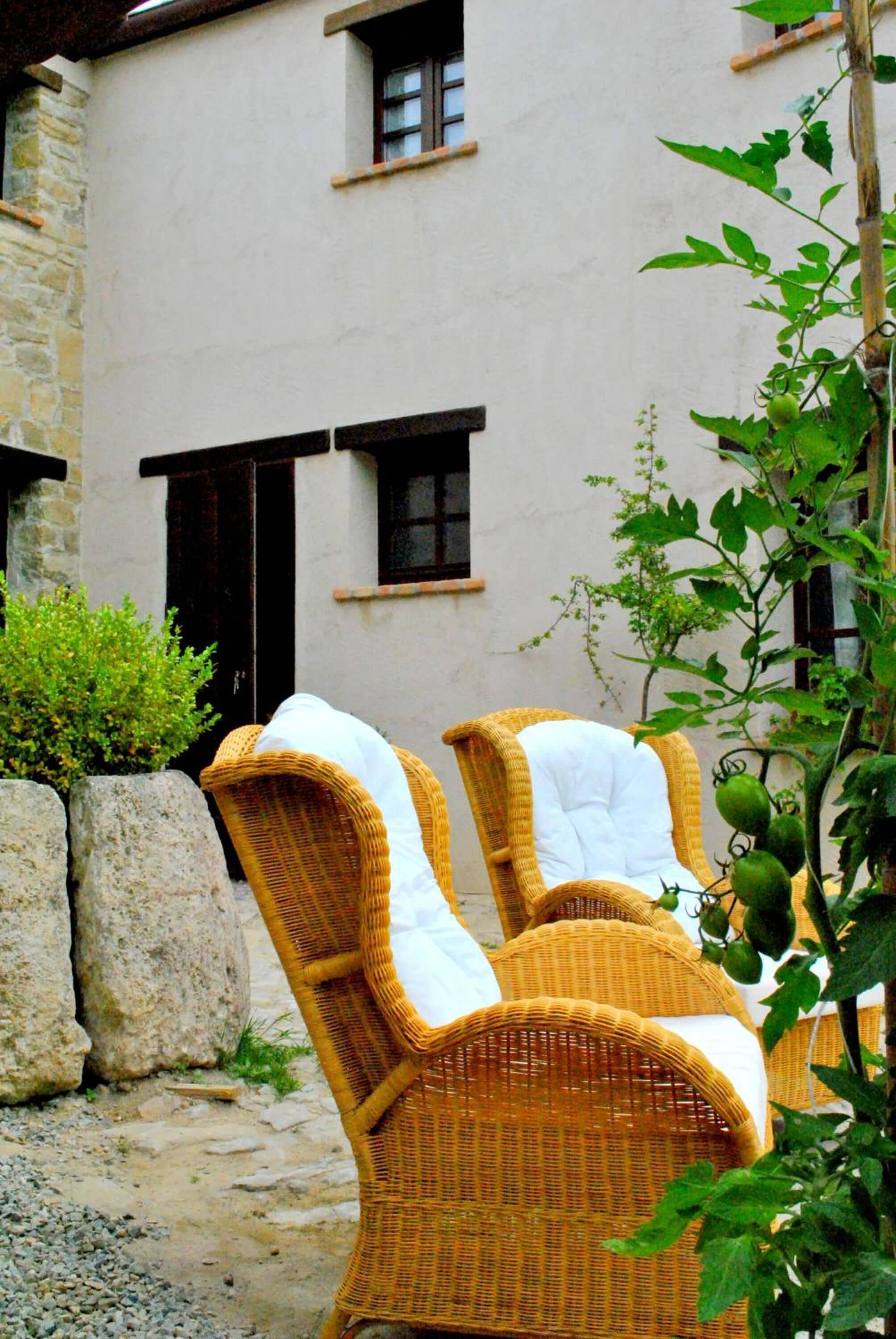 Wicker chairs with white cushions in an outdoor setting.