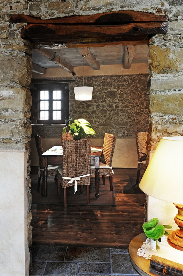 A rustic dining area with stone walls, wooden flooring, and wicker chairs. - Antica Locanda Lunetta (Mandas)