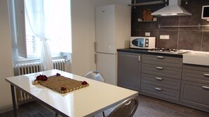 Una cocina moderna con una mesa blanca, armarios grises, un microondas y una estufa a gas.