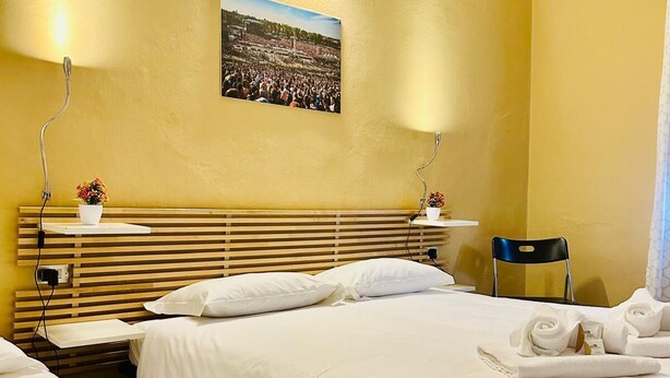 Ein Hotelzimmer mit zwei Betten, einem Holz-Kopfteil, einem Wandbild und einem Sessel.