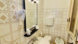 Ein Badezimmer mit Waschbecken, Spiegel, Haartrockner, Toilette, Bidet und Handtuchhalter.