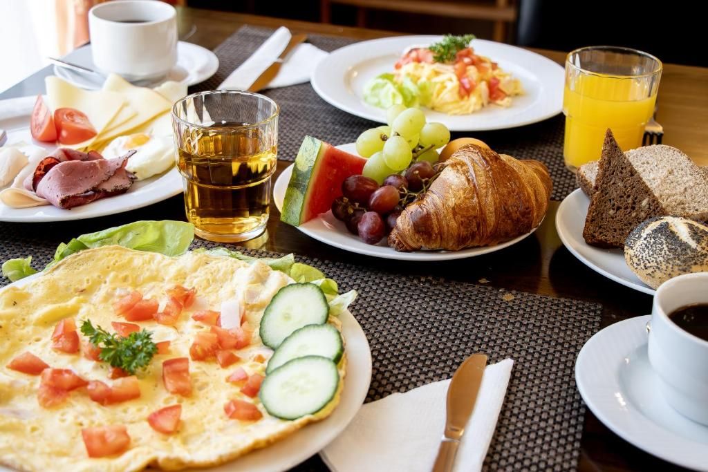 A breakfast setting with plates of food, a glass of juice, and a cup of coffee.