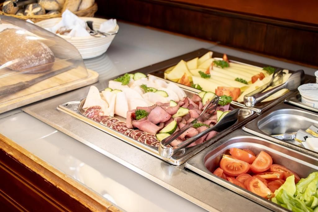 A buffet with various food items including meats, cheeses, and vegetables.
