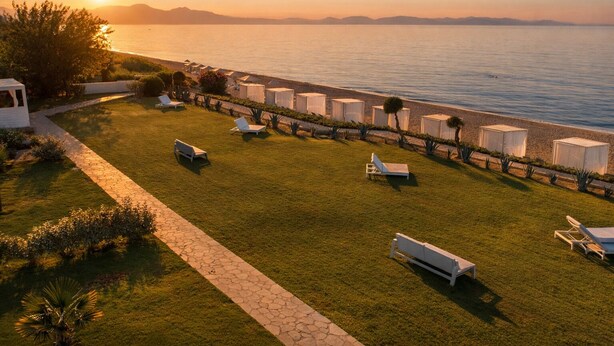 A coastal resort with a grassy lawn, sun loungers, and beach huts.