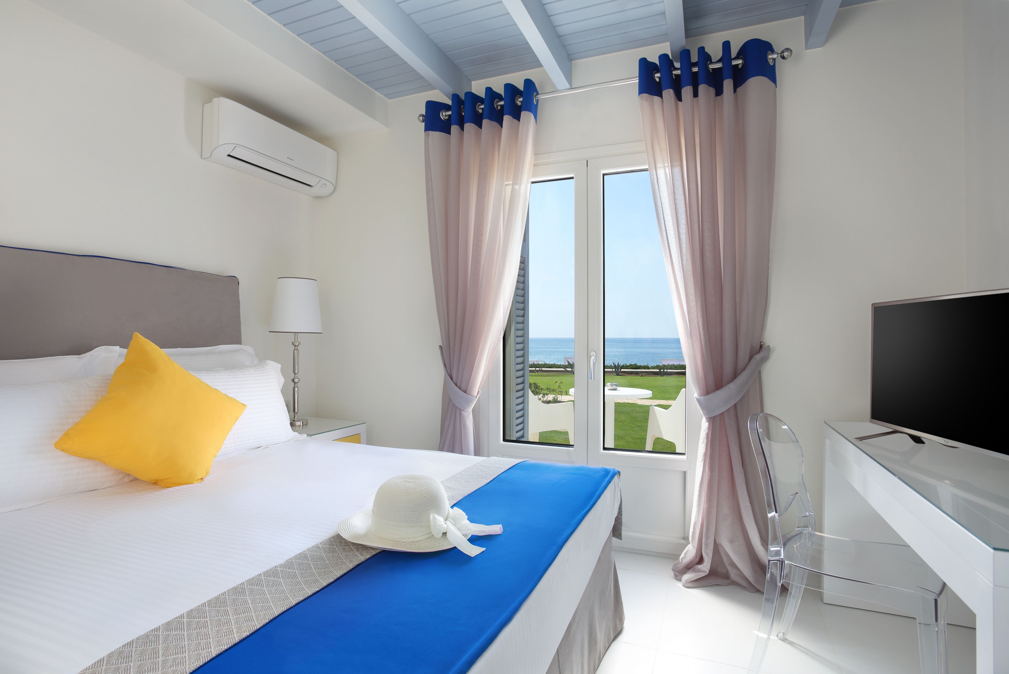 Habitación de hotel con cama, escritorio, televisión y vistas al exterior.