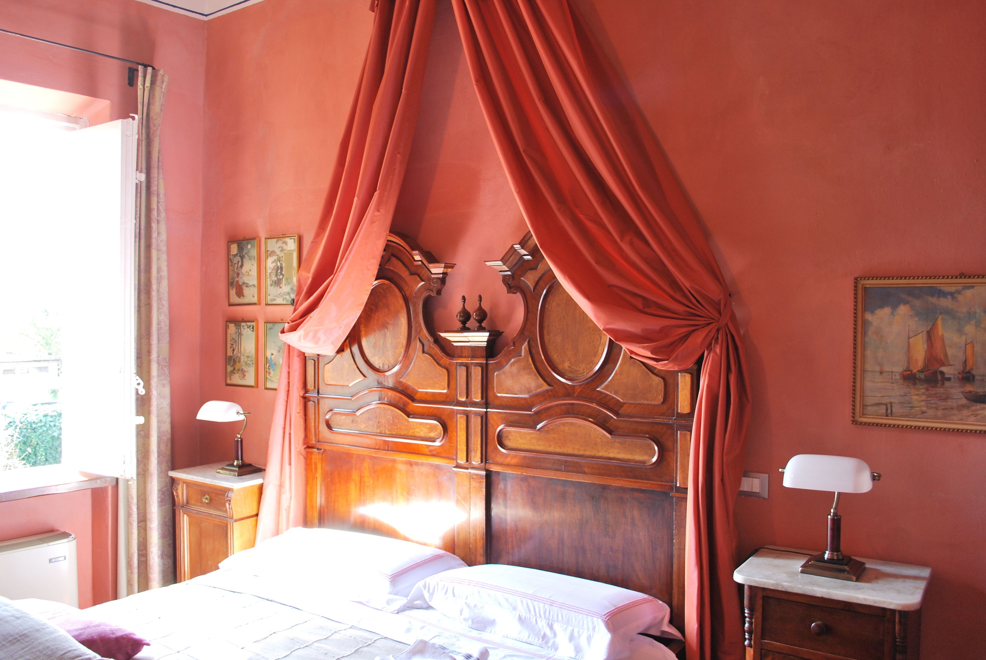 Una camera da letto con un letto a baldacchino, un comodino con una lampada e un quadro appeso al muro.