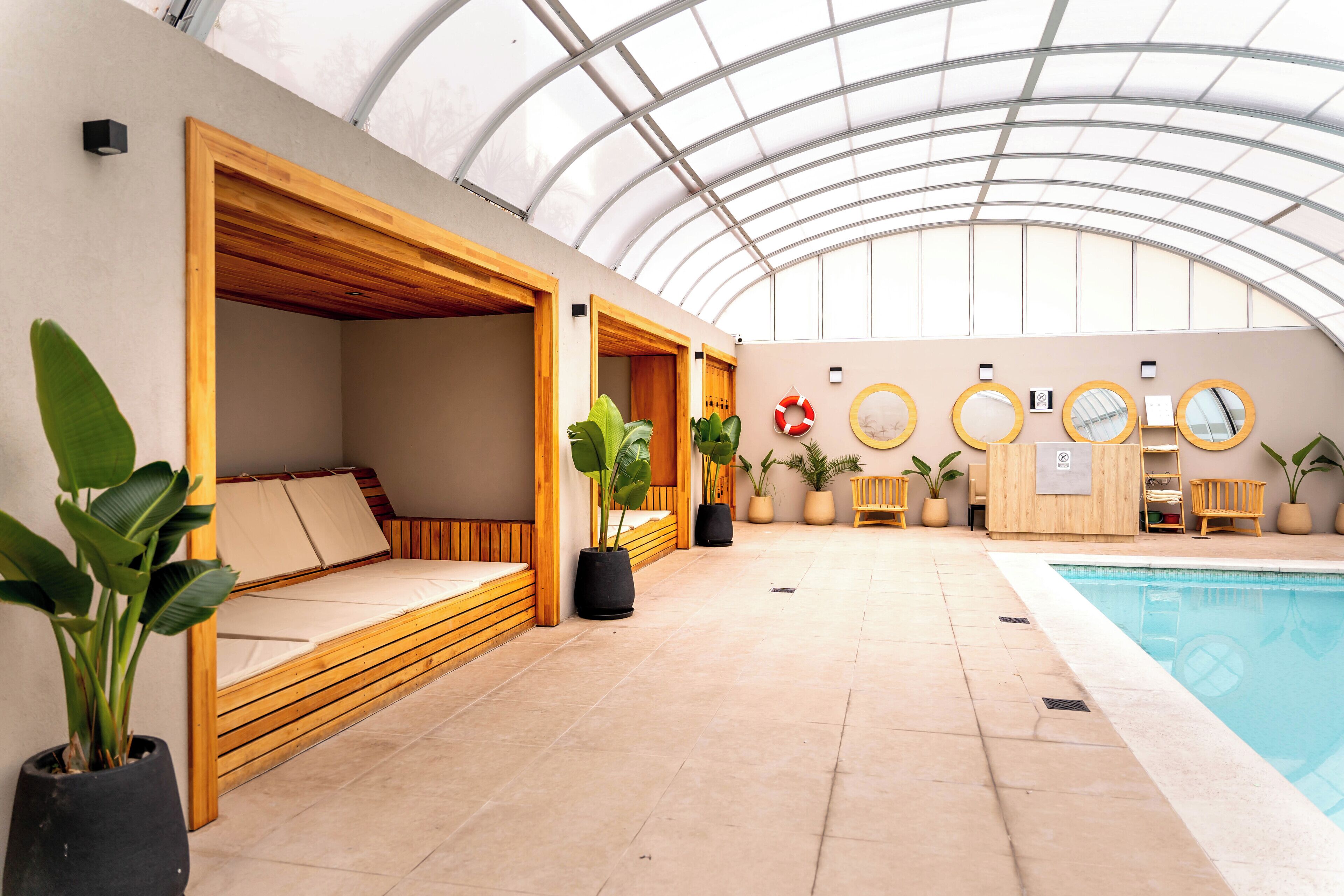 A spa area with wooden seating, a pool, and potted plants.