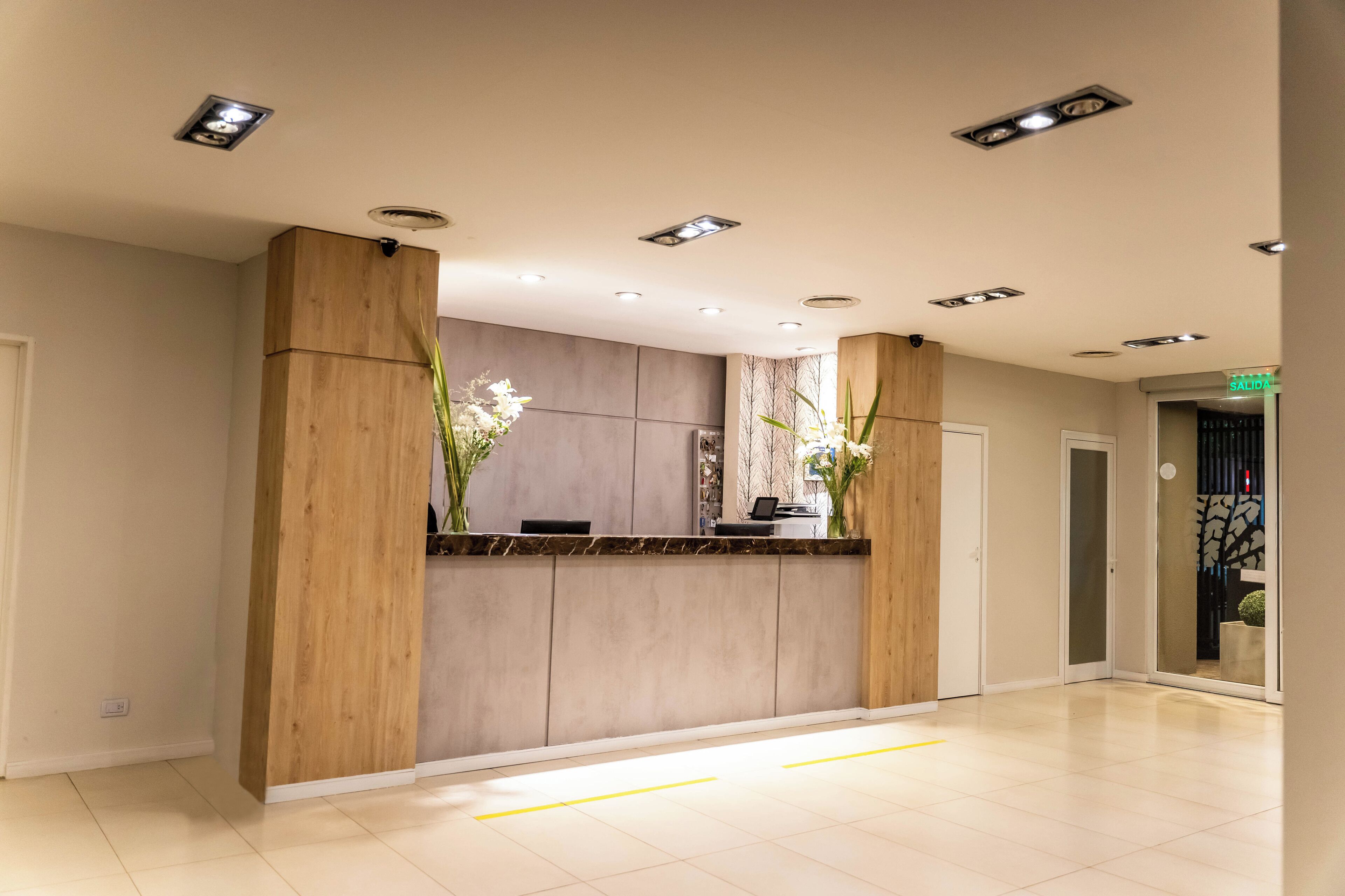 A modern reception area with a wooden reception desk, a marble countertop, and a large window with a view of the outdoors.