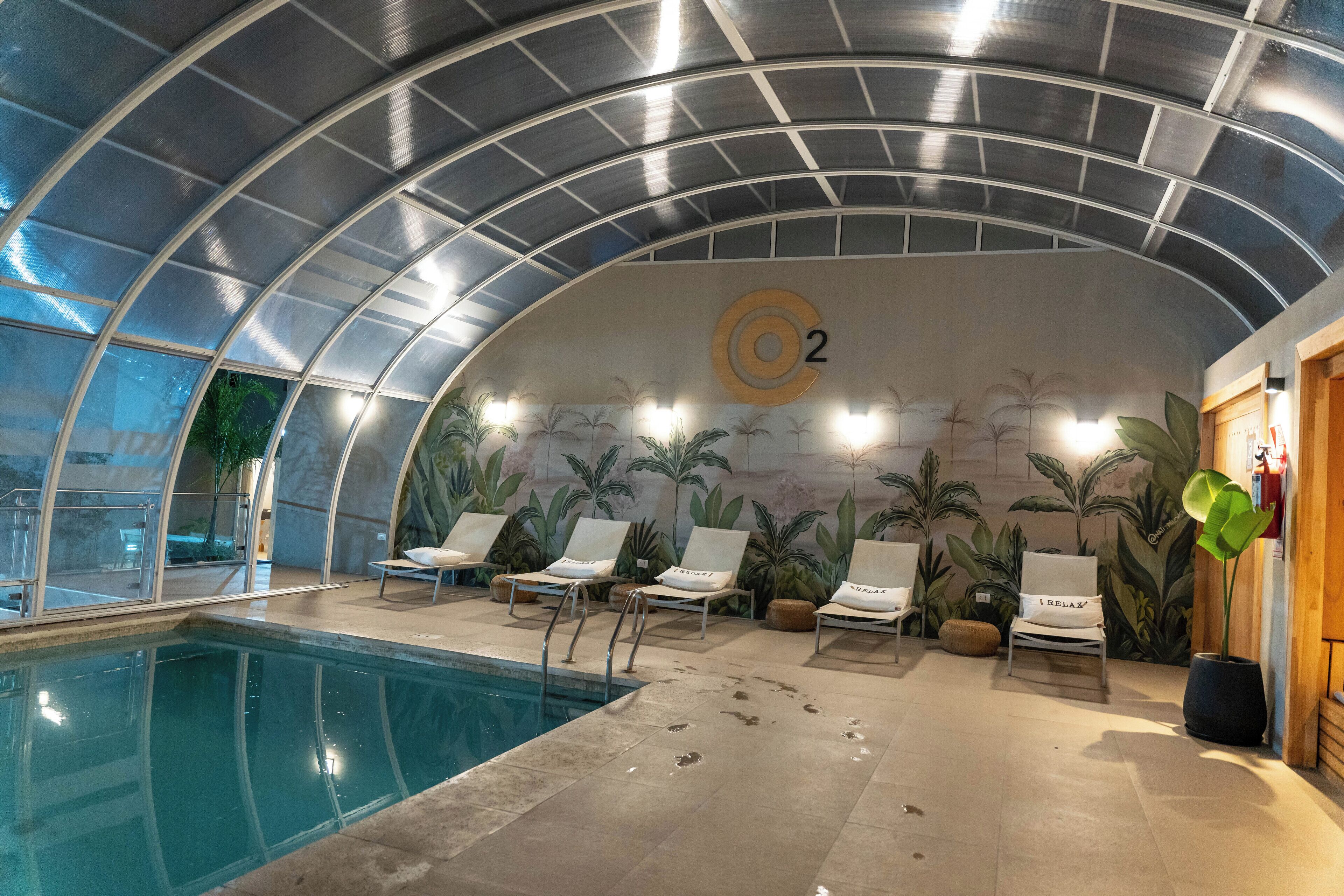 An indoor swimming pool with lounge chairs and a tropical mural.