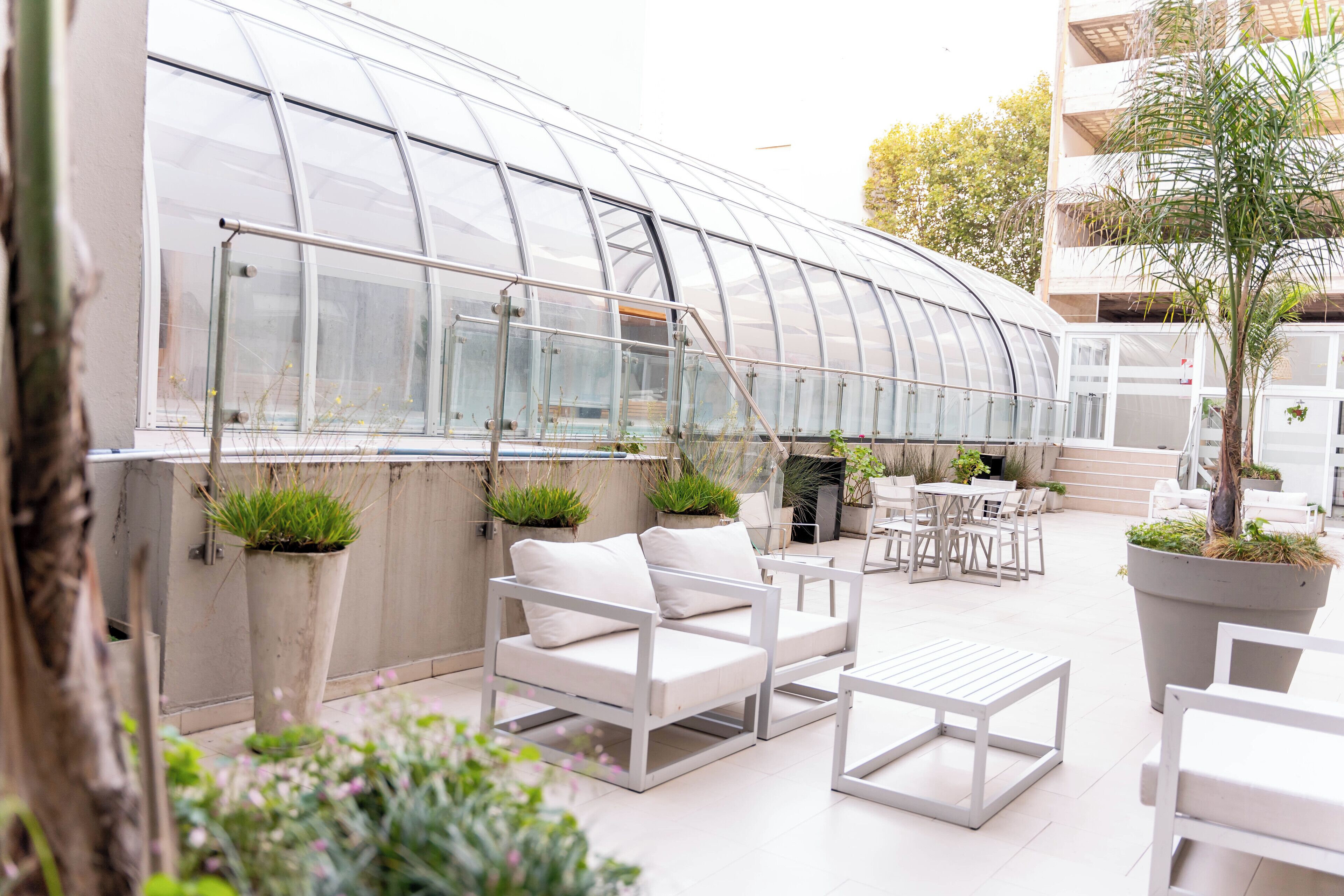 A greenhouse with white furniture, including sofas and tables, and potted plants.