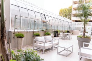 A greenhouse with white furniture, including sofas and tables, and potted plants.