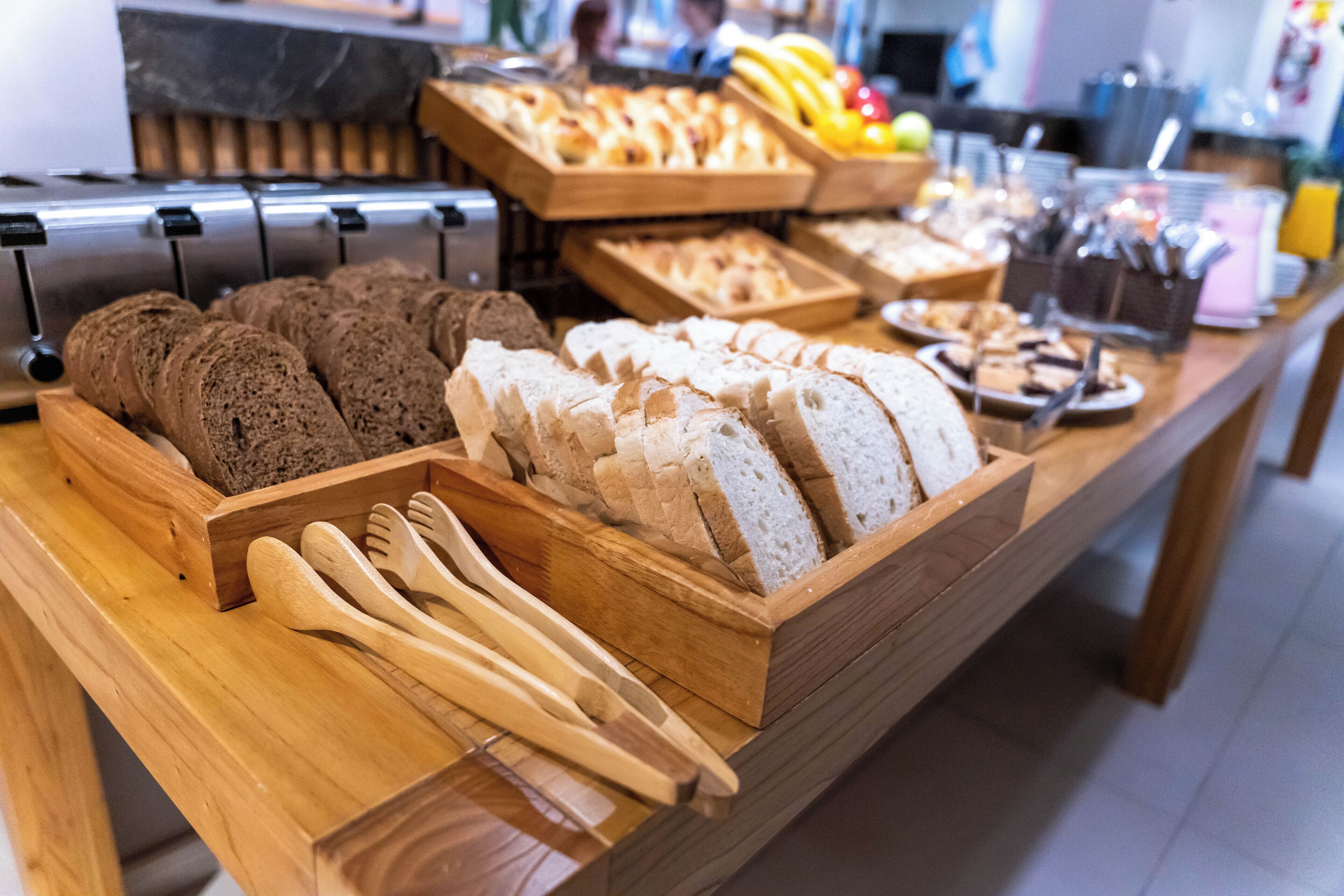 A buffet with various breads and utensils.