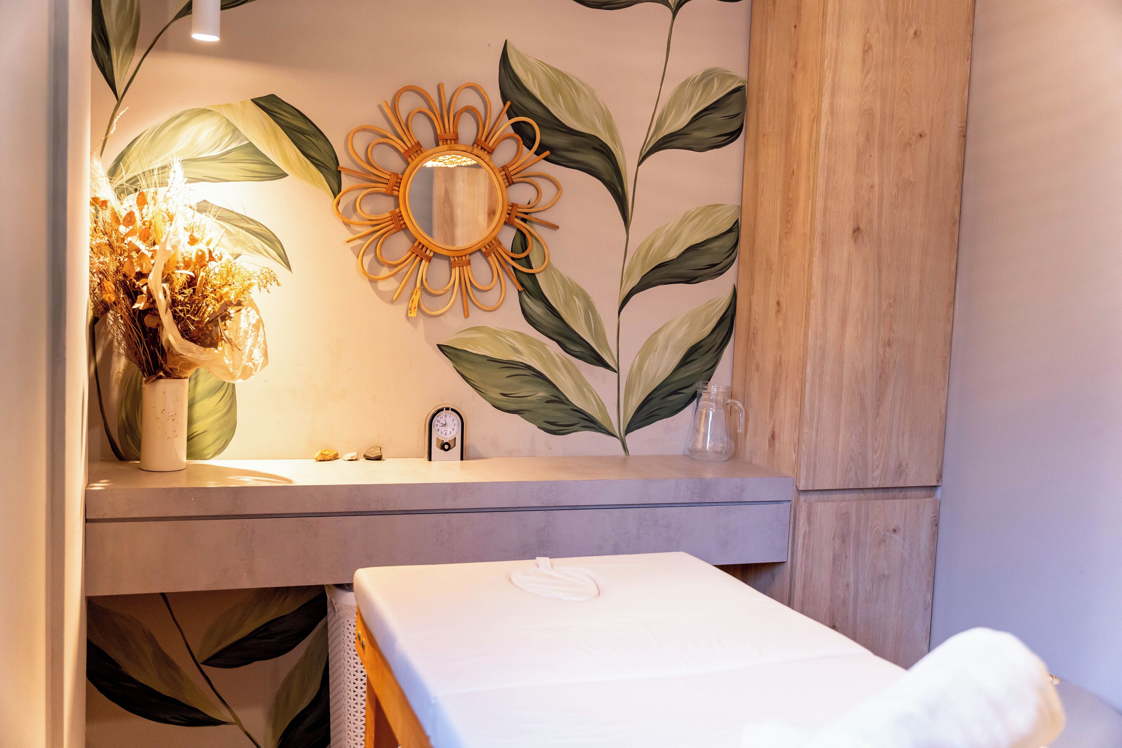 Une salle de bain avec un meuble-lavabo en bois, un miroir, une horloge et un lit.