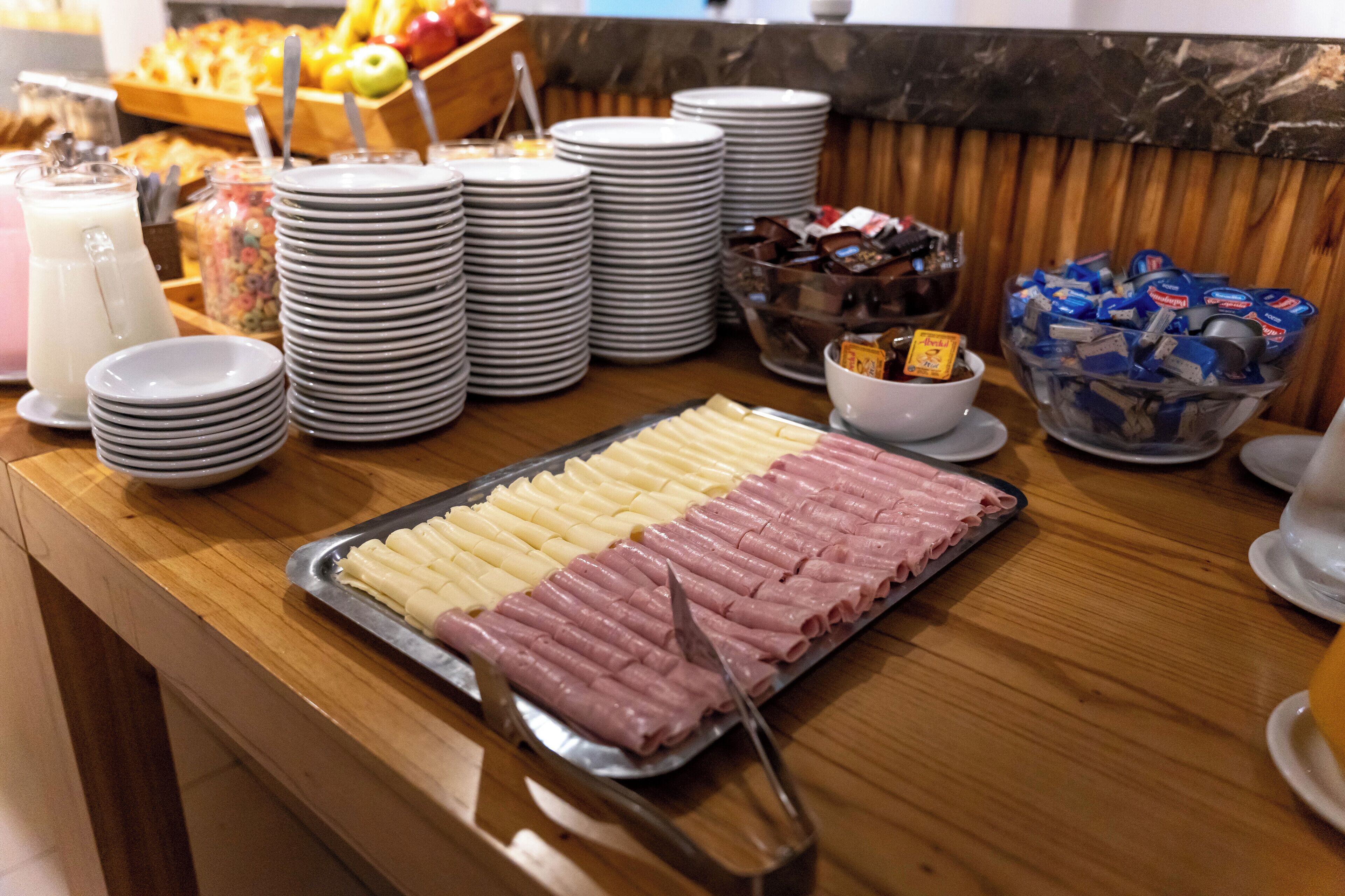 Une table de buffet avec des assiettes, des bols et des plateaux remplis de nourriture, notamment des pâtes et des viandes en tranches.