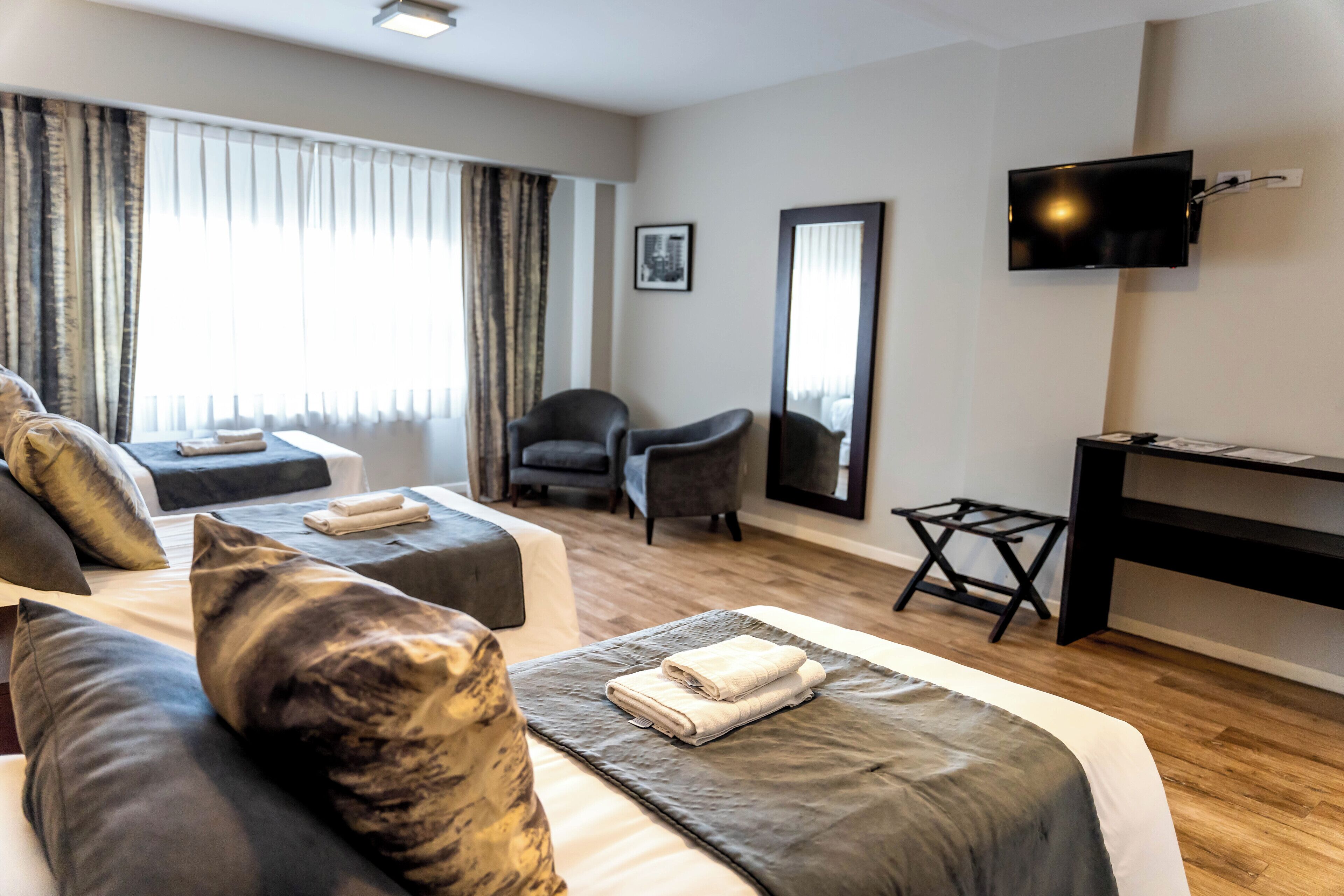 A hotel room with a large bed, two armchairs, a desk, and a TV.