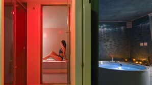 A woman sitting on a bench in a red-lit room, a large bathtub, and a wall with fish decorations. - Duomo Suites & Spa (Catania)