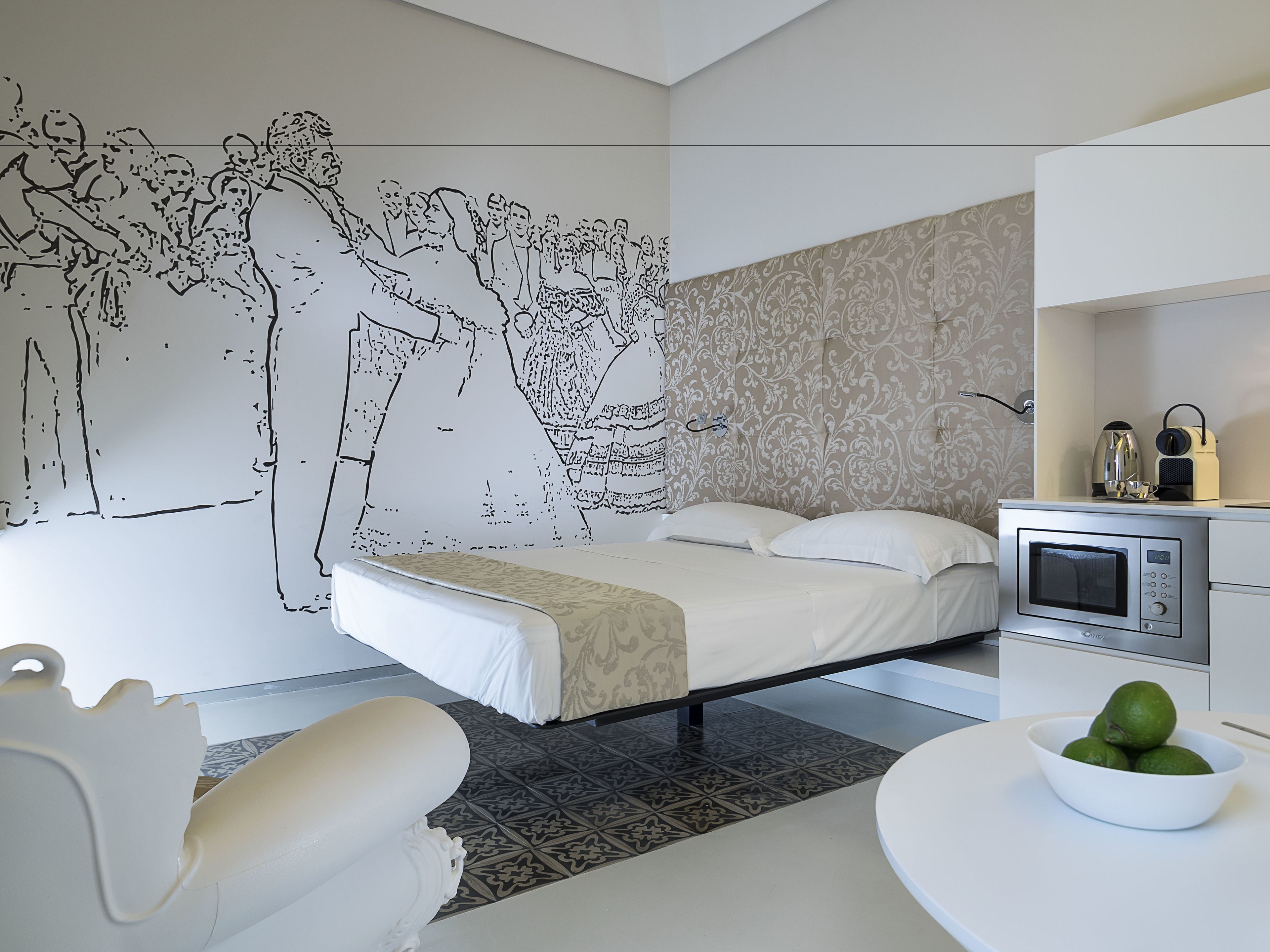 Un dormitorio moderno con una cama grande, una pequeña kitchenette y un mural en la pared.