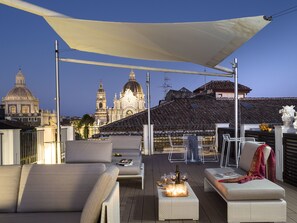 A rooftop terrace with seating, a table with candles, and a view of historic buildings. - Duomo Suites & Spa (Catania)