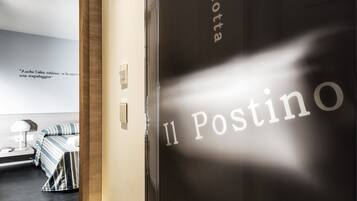 A hotel room with a bed, a bedside table, and a wall with a quote.