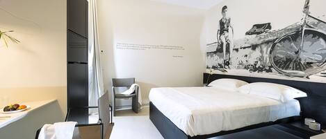 A modern hotel room with a bed, a chair, a desk, and a large wall mural.
