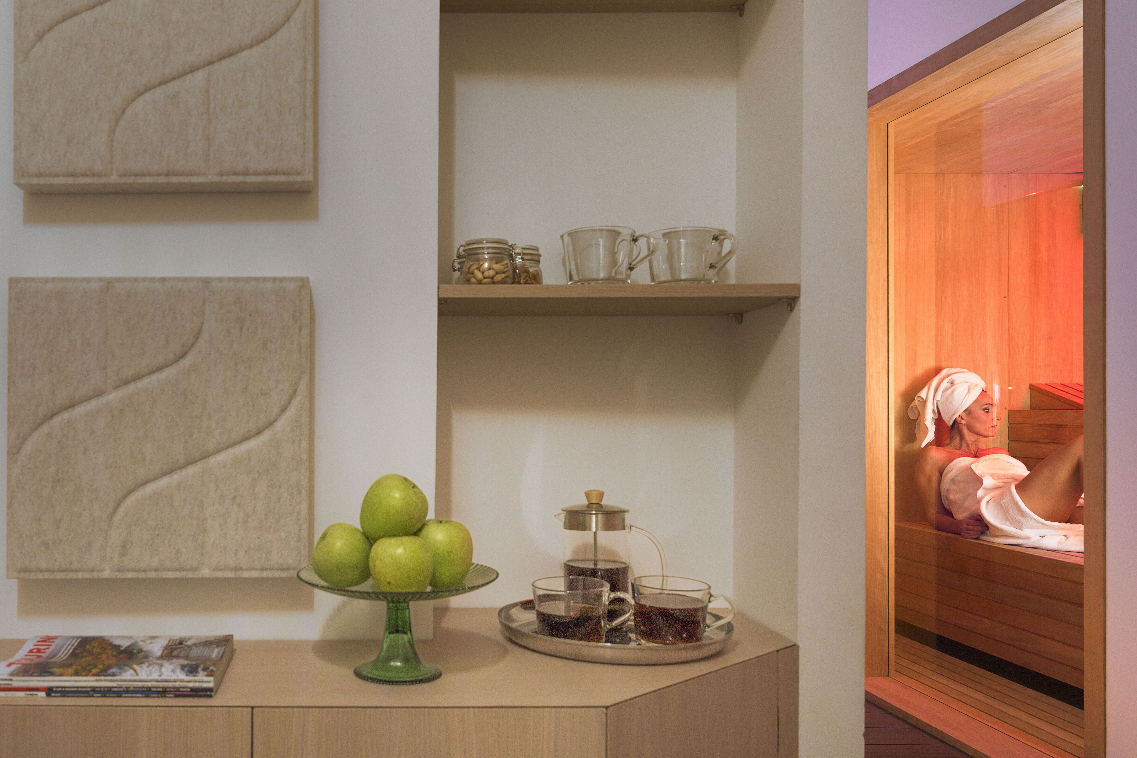 Een kamer met een houten kast, een groene fruitstand, een koffiezetapparaat en een tijdschrift op het aanrecht.