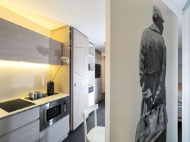 Una cucina moderna con elettrodomestici integrati, una sedia bianca e un'opera d'arte appesa al muro.