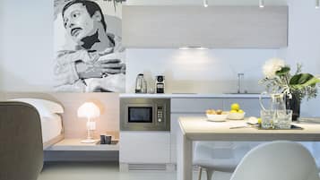 A modern kitchen with a microwave, kettle, and a small dining area with a table and chairs.
