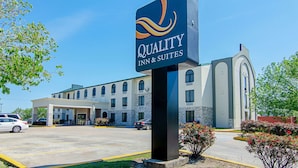 A hotel sign with "Quality Inn & Suites" branding, a parking lot, and a building with a covered entrance. - Quality Inn & Suites Near Tanger Outlet Mall (Gonzales)