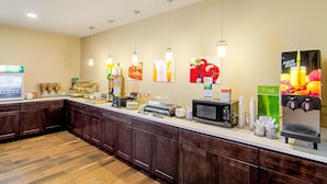 A breakfast bar with a microwave, coffee machine, and juice dispenser. - Quality Inn & Suites Near Tanger Outlet Mall (Gonzales)