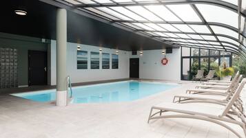 An indoor swimming pool with clear glass ceiling, lounge chairs, and a lifebuoy.