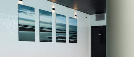 A pool area with a tiled floor, a metal handrail, and three framed pictures on the wall.