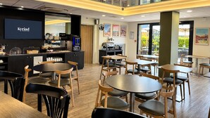 A restaurant with a counter, seating area, and a TV screen displaying 'Kyriad Prestige'.