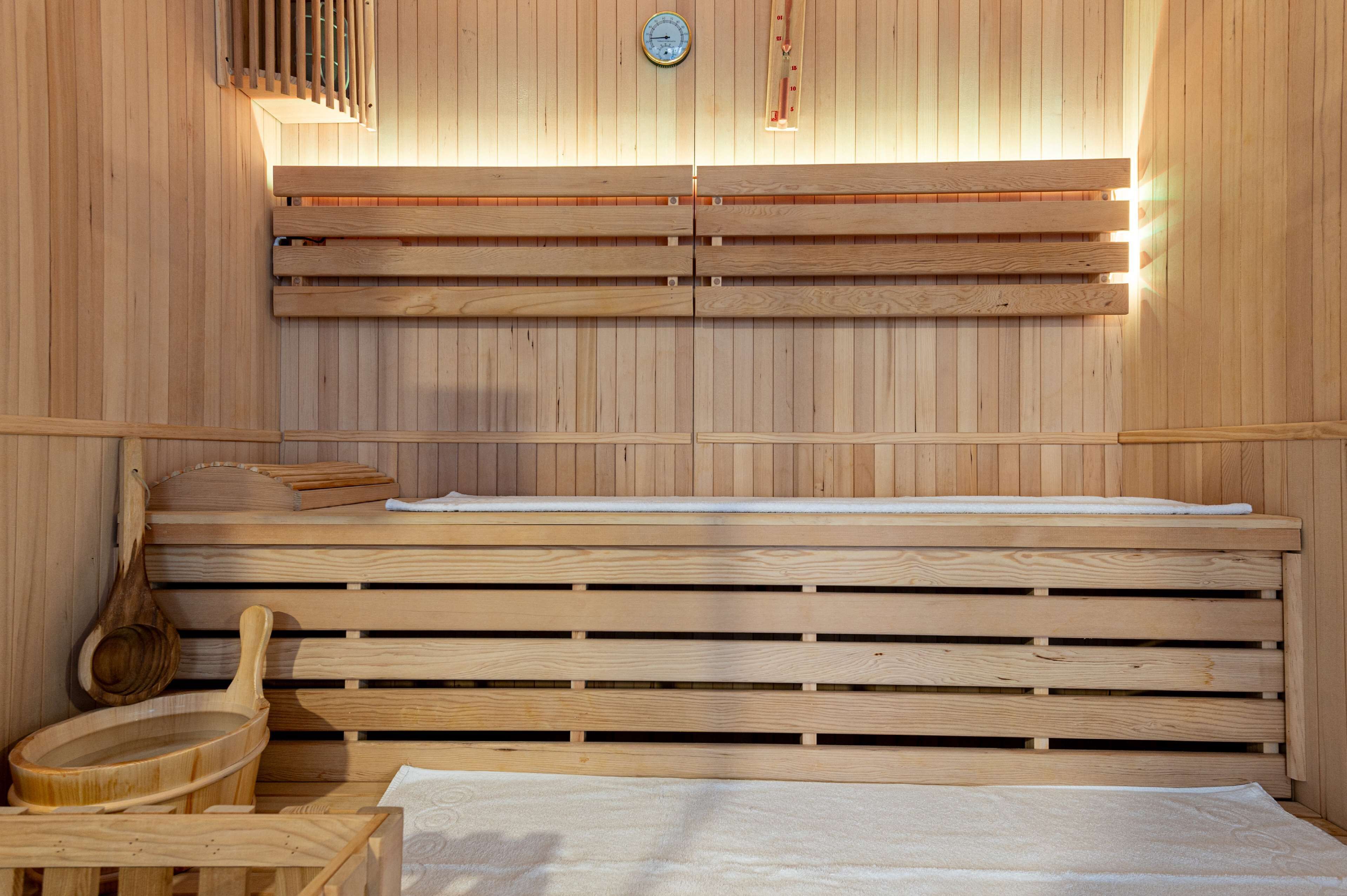 A sauna with wooden benches, a clock, and a wooden ladle.