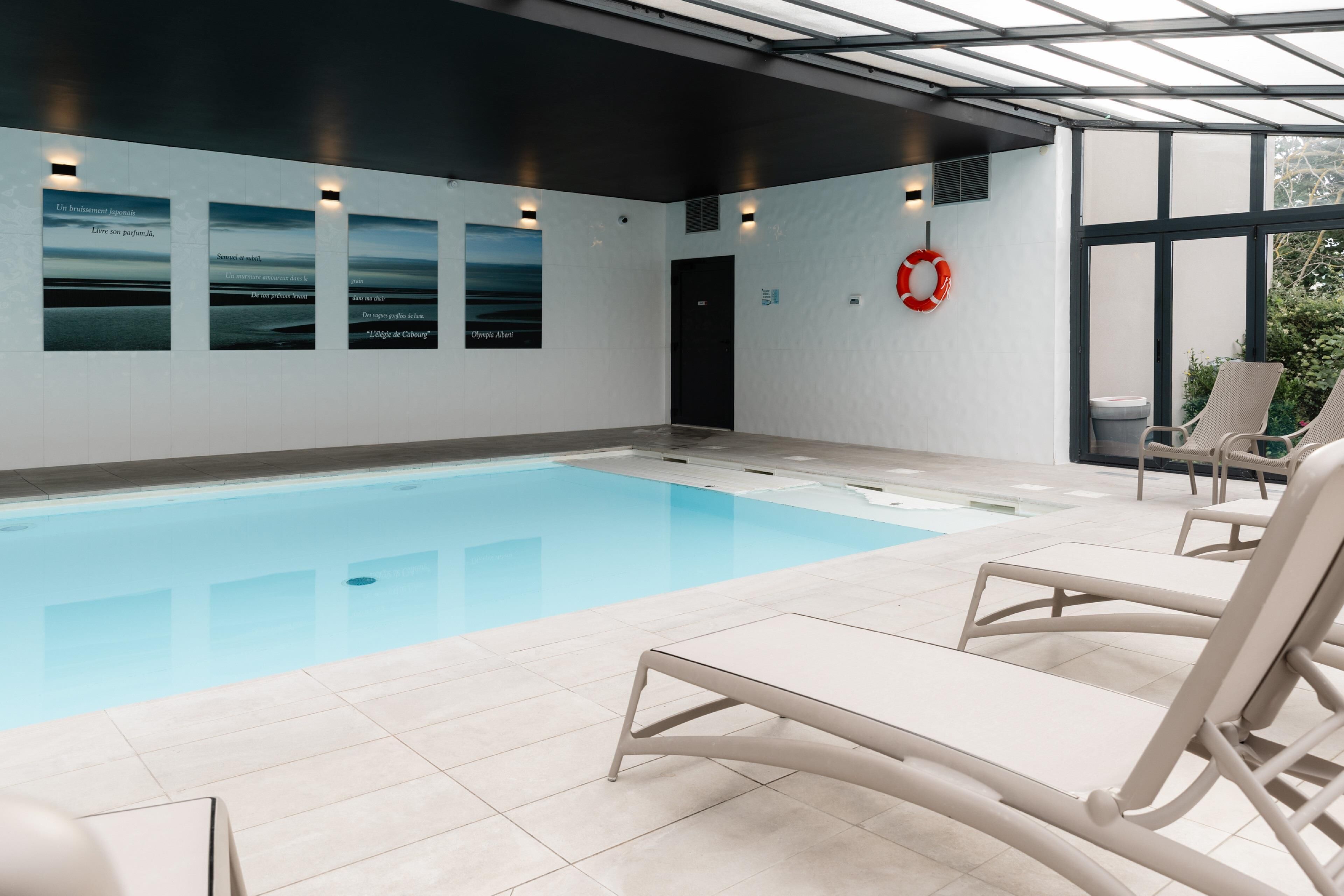 Una piscina con sillones de descanso, un flotador salvavidas y carteles en la pared.