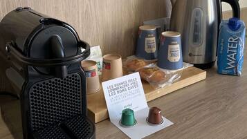 Una cocina equipada con cafetera, hervidor y varios vasos de café, además de una jarra de agua.