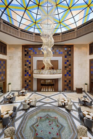 A spacious lobby with a high ceiling, a central decorative column, and a patterned floor. - Souq Waqif Boutique Hotels by Tivoli (Doha)