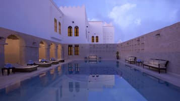 A pool area with lounge chairs and a spa.