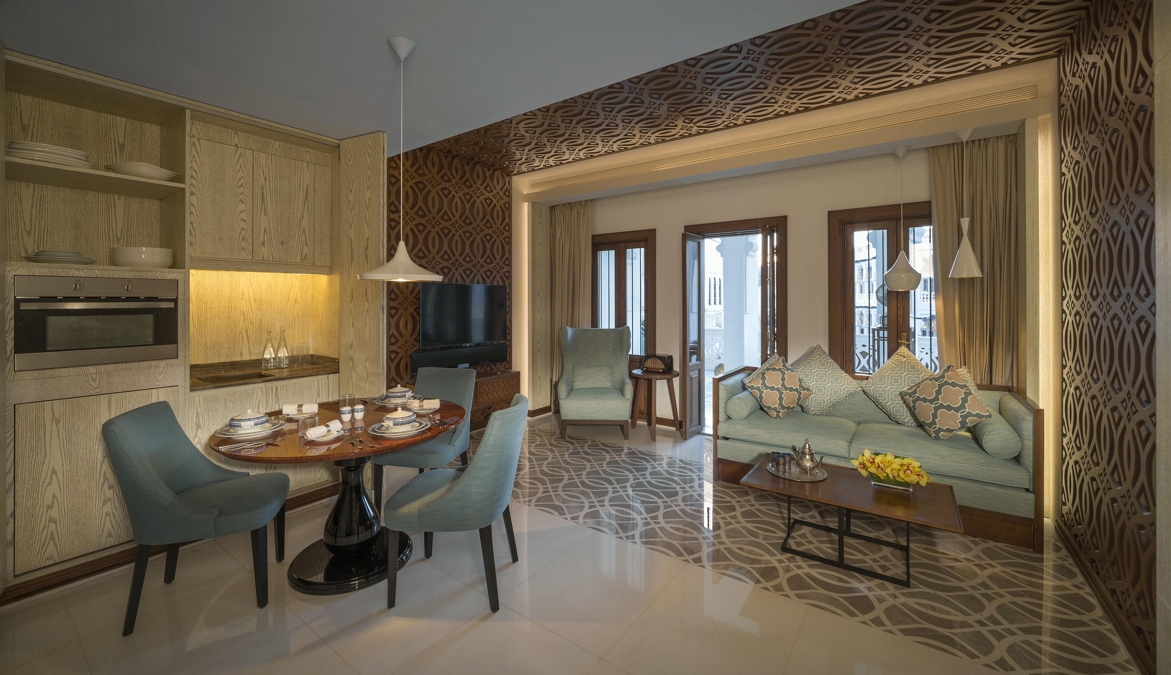 A modern living room with a dining area, a sofa set, a television, and a patterned wall.