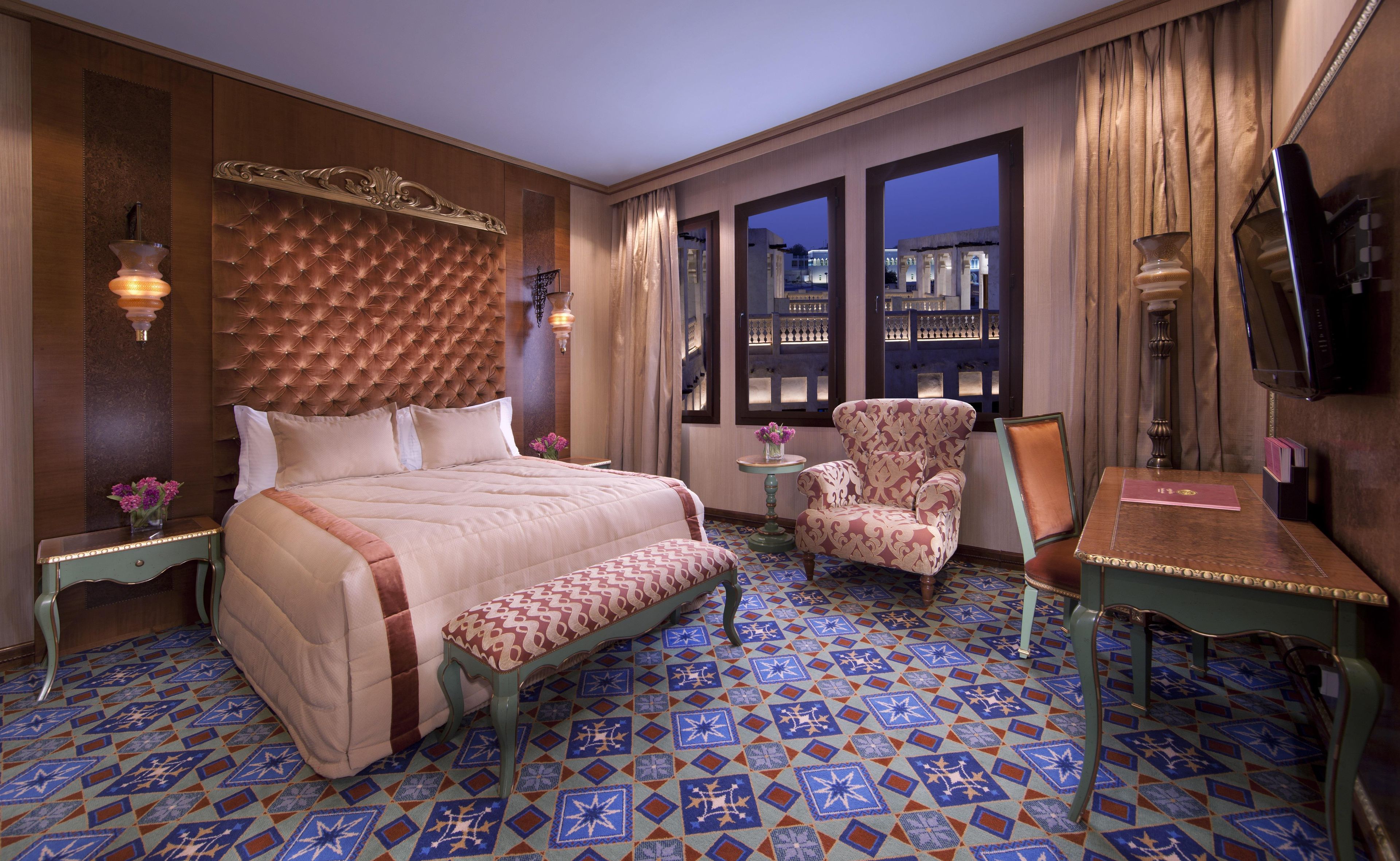Habitación de hotel con una cama grande, una silla, una mesita y un televisor.