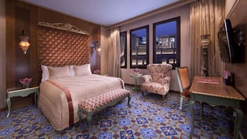 Habitación de hotel con una cama grande, una silla, una mesita y un televisor.