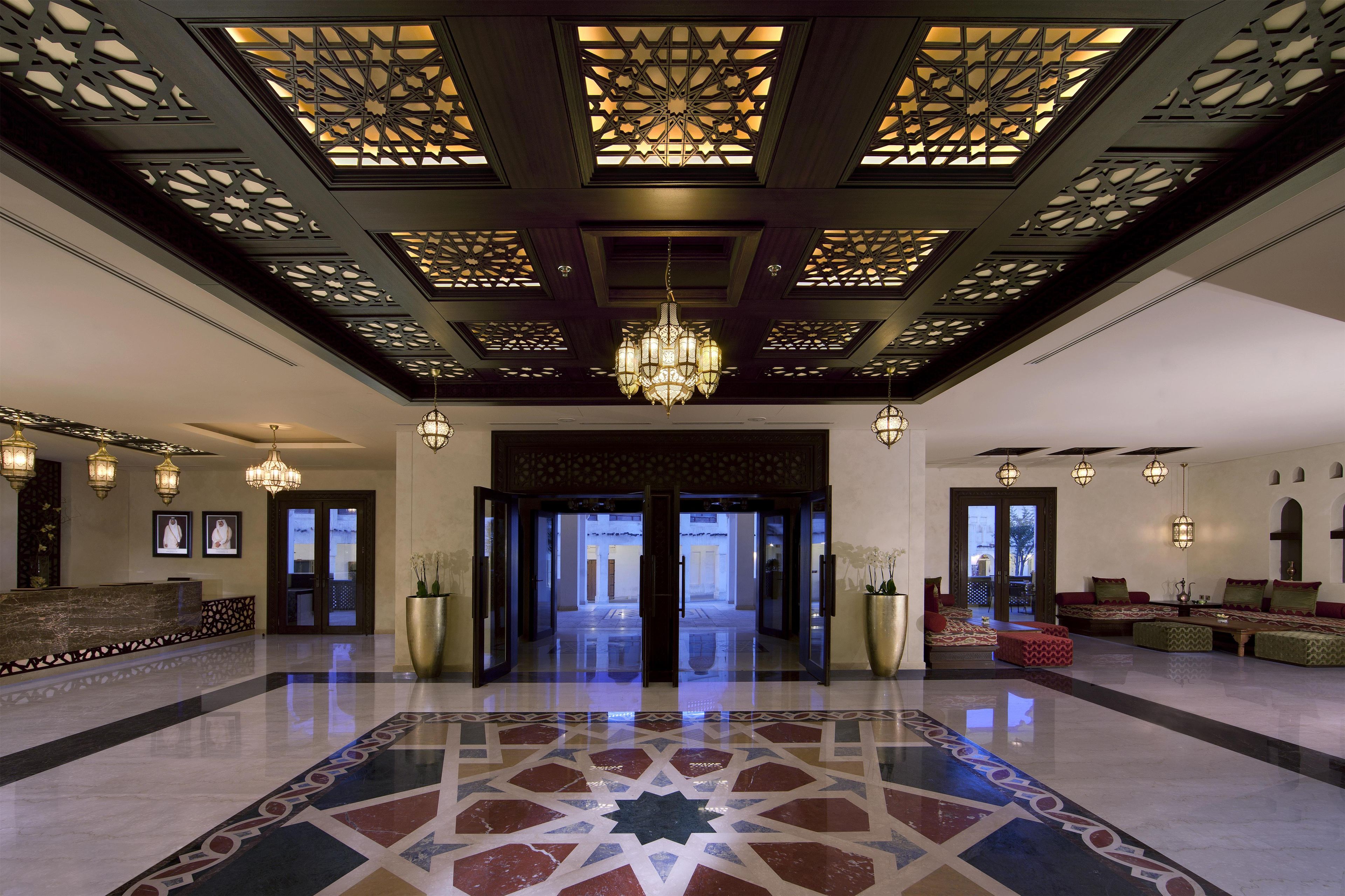 Eine geräumige Lobby mit einem geometrischen Fußbodenmuster, einem prächtigen Chandelier und klassischer Einrichtung.