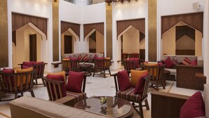 A spacious lobby with multiple seating areas, including sofas and chairs, arranged around a central coffee table. - Souq Waqif Boutique Hotels by Tivoli (Doha)