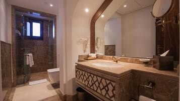 A modern bathroom with a glass-enclosed shower, a marble sink, and a large mirror.
