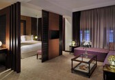 A hotel room with a bed, a sofa, a coffee table, and a TV.