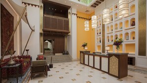 A lobby with a reception desk, patterned carpet, and a decorative wall with shelves. - Souq Waqif Boutique Hotels by Tivoli (Doha)