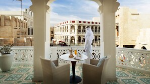 A balcony with wicker chairs, a table with a pitcher, a glass of orange juice, and a cup of coffee. - Souq Waqif Boutique Hotels by Tivoli (Doha)