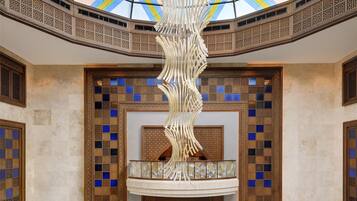 Un hall d’entrée spacieux avec un plafond haut, une colonne centrale décorative et un sol à motifs.