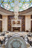 A spacious lobby with a high ceiling, a central decorative column, and a patterned floor.