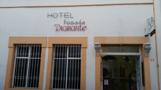 A hotel named "HOTEL Posada Diamante" with two windows featuring metal bars and a door with a sign indicating it is a public restroom. - Hotel Posada Diamante (Querétaro)