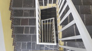 A spiral staircase with white railings, leading downwards. - Hotel Posada Diamante (Querétaro)